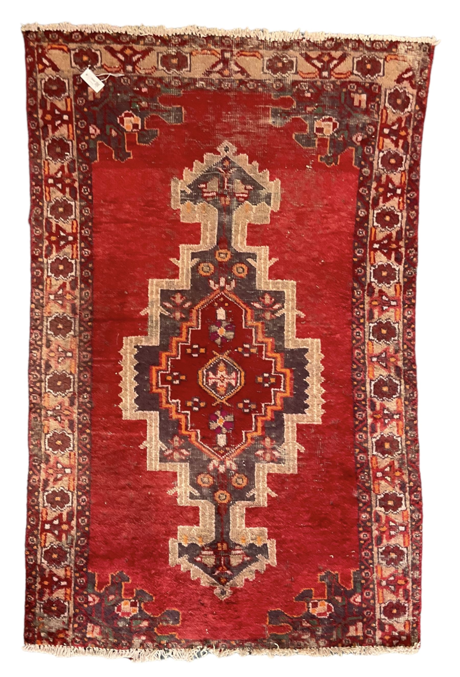 Persian red ground rug, the field decorated with geometric pole medallion, floral decorated spandrels and repeating border 