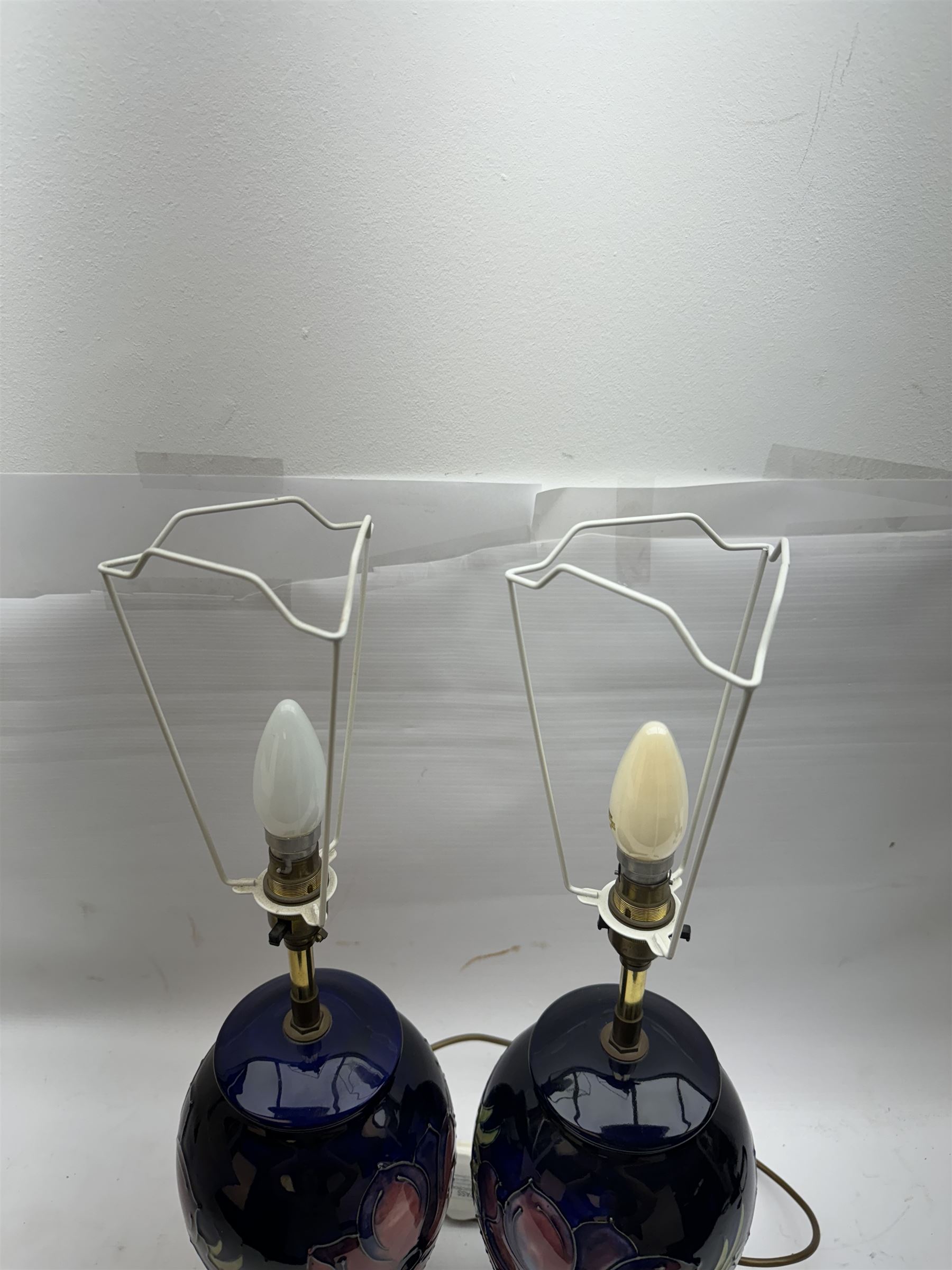 Pair of Moorcroft table lamps, in Anemone patter, upon a blue ground, with cream lampshades, H68