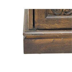 Mid 20th century oak bookcase cupboard, projecting cornice over three open shelves with subdivided sections and latticework uprights, two doors to the base with floral and scrollwork carvings and central brass handles, resting on a moulded plinth base