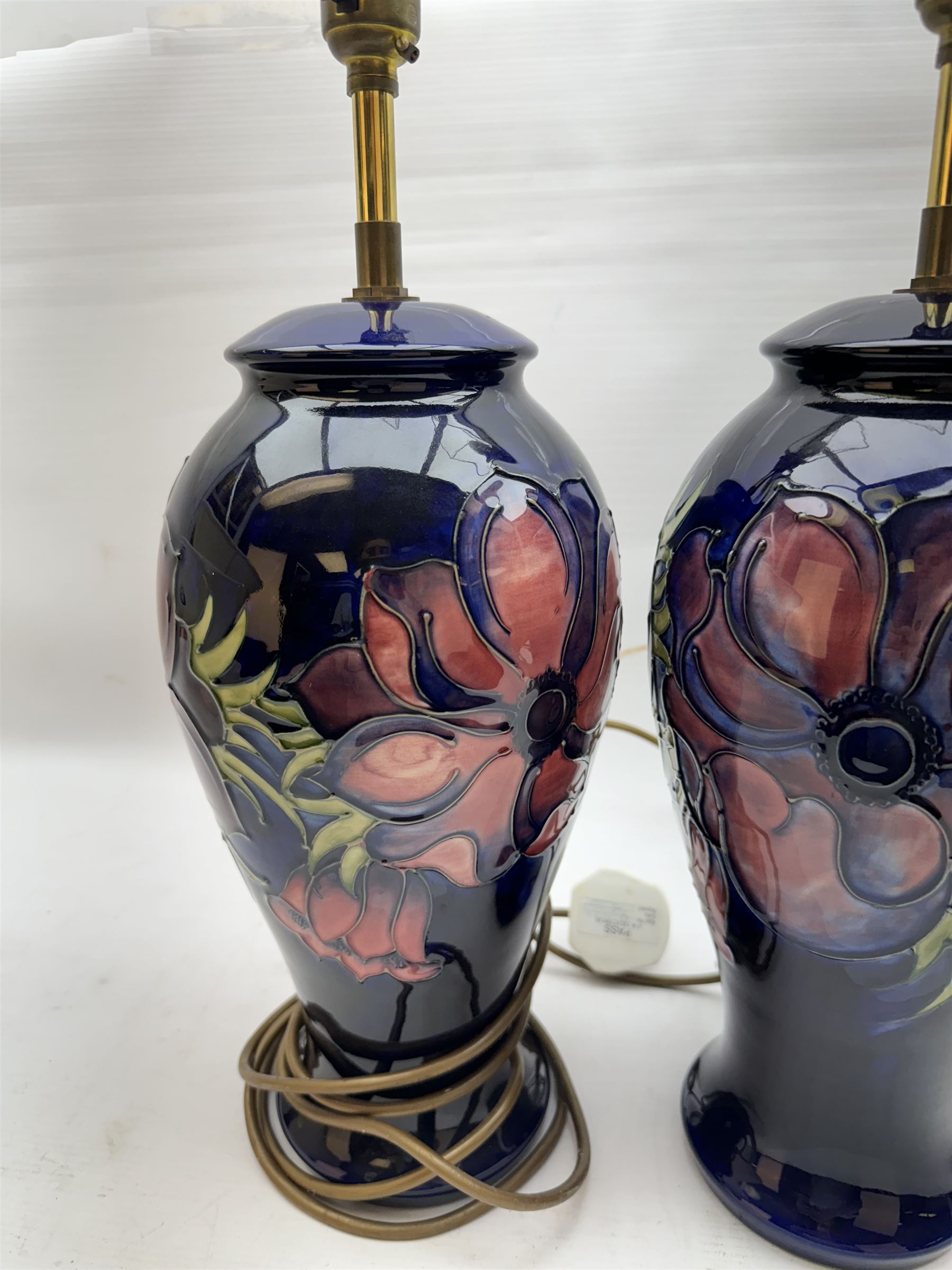 Pair of Moorcroft table lamps, in Anemone patter, upon a blue ground, with cream lampshades, H68