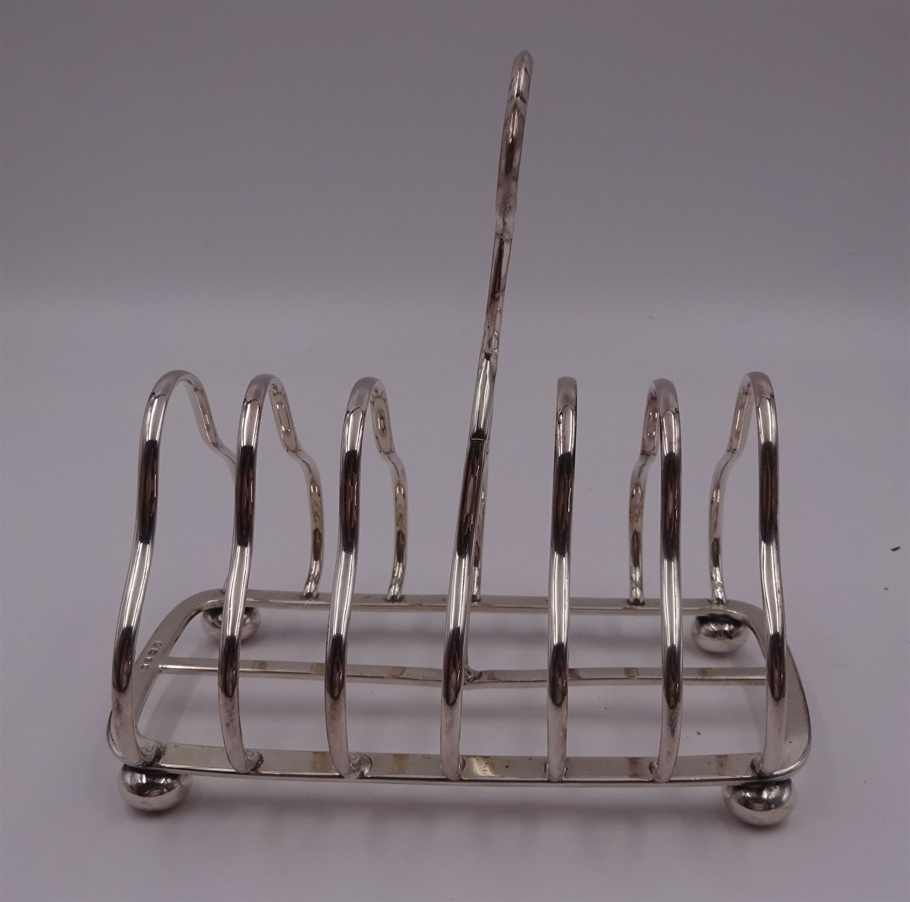 Victorian silver seven bar toast rack, each bar of trilobed form, with similar loop handle and upon four bun feet, hallmarked John Gilbert, Birmingham 1863, H16.5cm