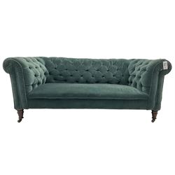 Victorian hardwood-framed Chesterfield sofa, traditional shape with low back and rolled arms, upholstered in teal buttoned fabric, on turned front feet with brass and ceramic castors 