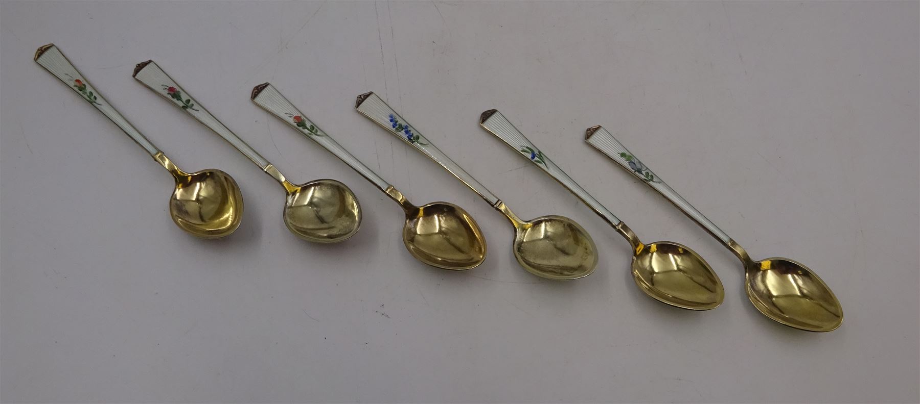 Set of six Norwegian silver-gilt and enamel demitasse spoons, decorated front and verso with small colourful flowers on a white ground,  925S Sterling, in retailers box for Magnus Aase, Bergen