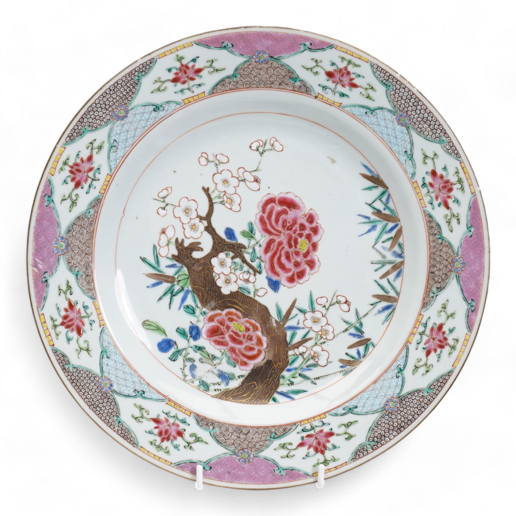 Set of nine Chinese Qianlong famille rose plates, comprising two large circular serving plates centrally enamelled with a blossoming tree branch and bamboo, within a cell diaper border, D32cm and seven side plates with matching decoration, D22.5cm 