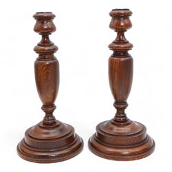 Pair of turned pine candlesticks with baluster stems, H30cm, together with a similar smaller candlestick (3)