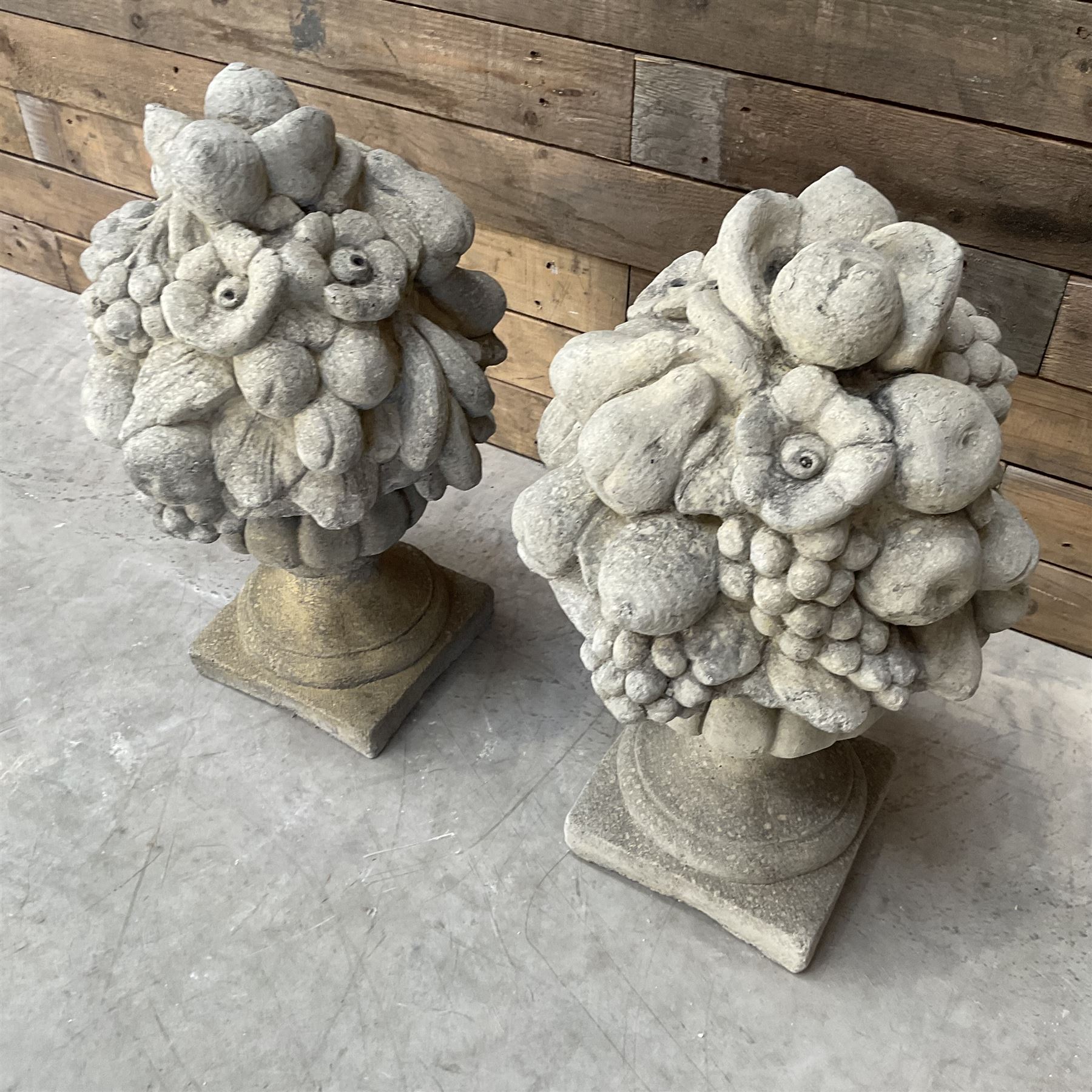 Pair of cast stone garden wall or gate finials depicting Fruit Piers, raised on separate circular squat column with plinth base