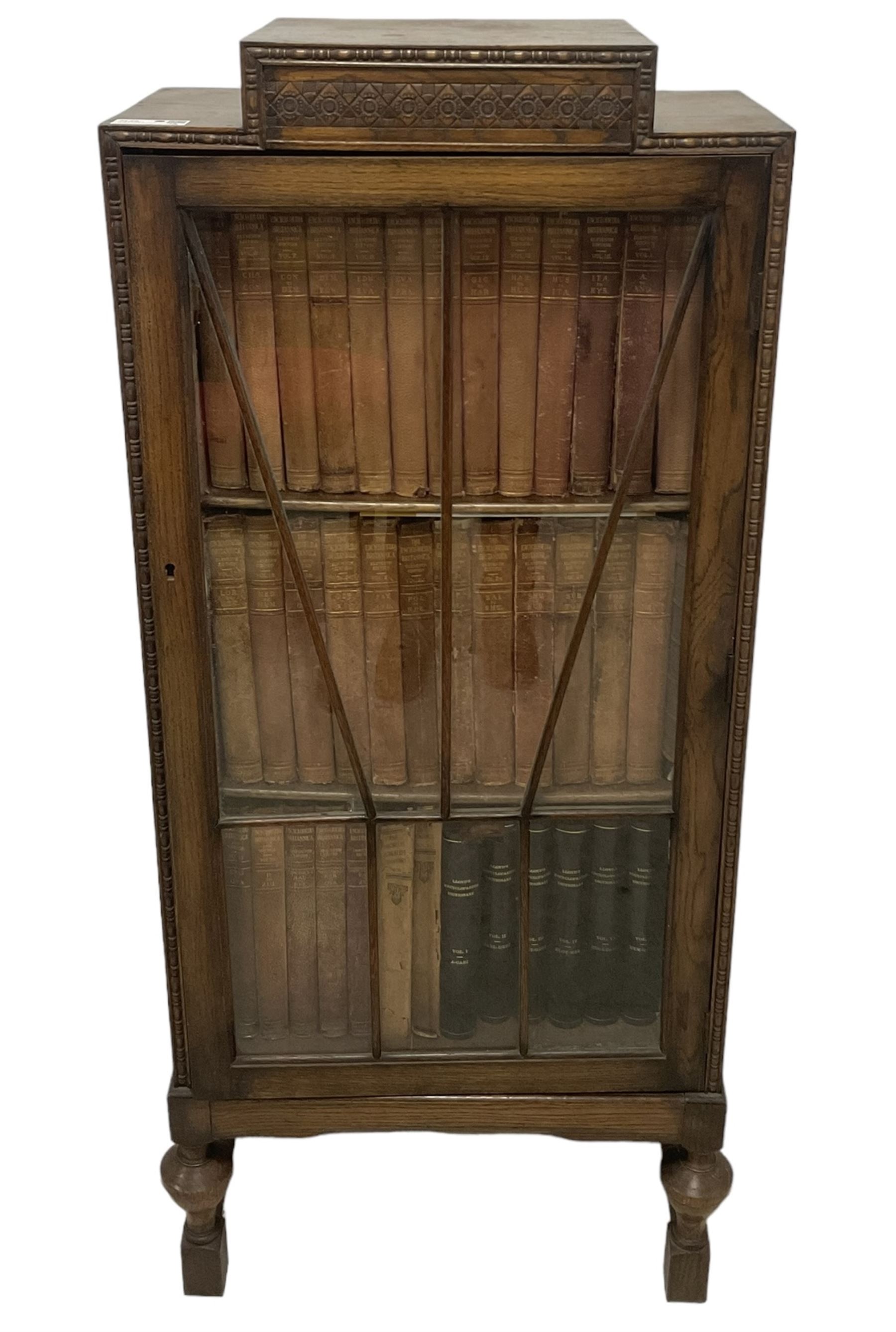 Edwardian oak bookcase, stepped top decorated with beading and stylised floral frieze, single astragal glazed door enclosing encyclopaedias and other books, on turned front feet united by plain stretchers 