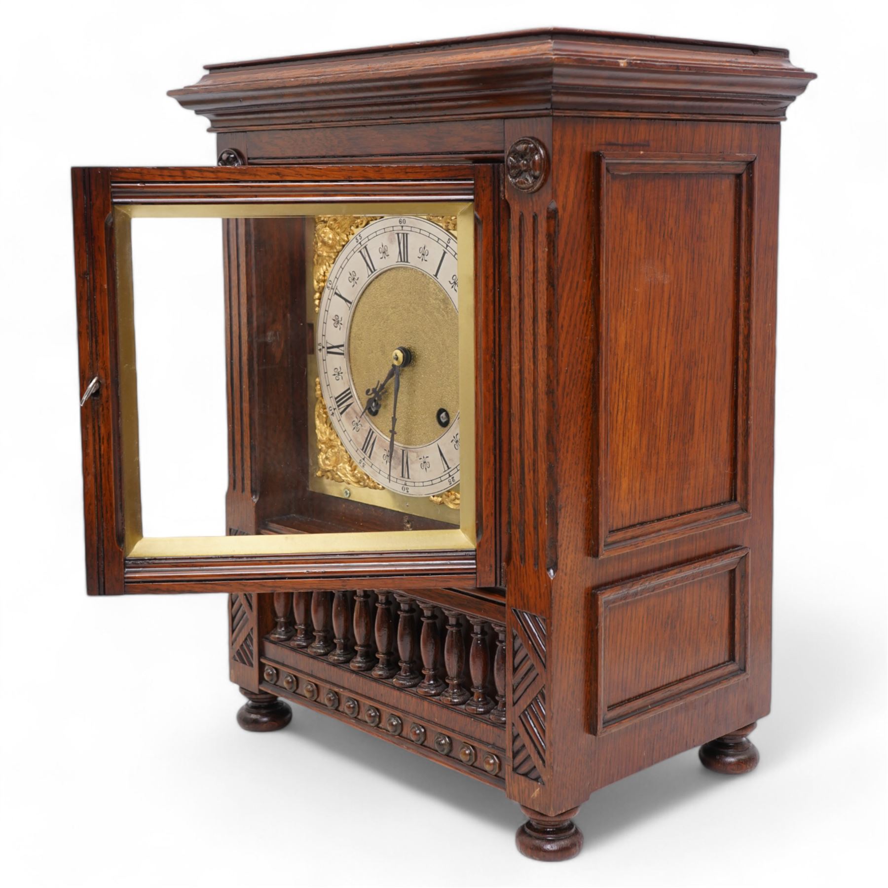 Lenzkirch - late 19th century German oak cased 8-day quarter striking mantle clock, with a flat top and moulded cornice beneath, carved decoration with a turned baluster gallery to the front, raised on bun feet, square brass dial with a matted centre and cast cherub spandrels, silvered chapter with Roman numerals and fleur-di-Lis steel hands, two train going barrel movement striking the quarters and hours on two coiled gongs. With pendulum and key.