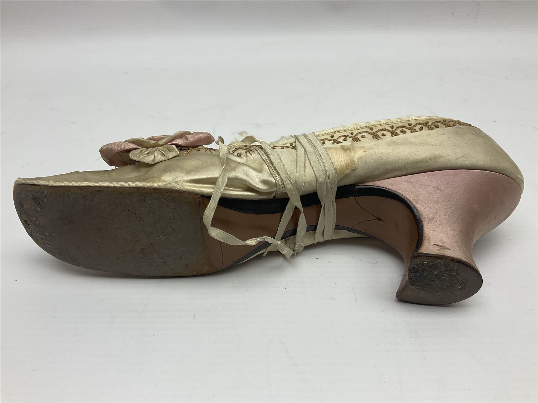 Pair of 19th century ivory silk satin ladies shoes, with rosette to the vamp, with pink silk satin heel, L23cm