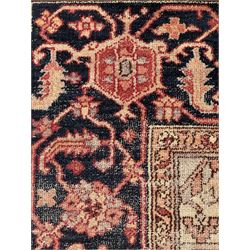 Persian Heriz design rug with red ground, the field featuring a central medallion with floral and geometric motifs, surrounded by ivory spandrels, the main border showcasing a series of floral patterns on a dark blue ground