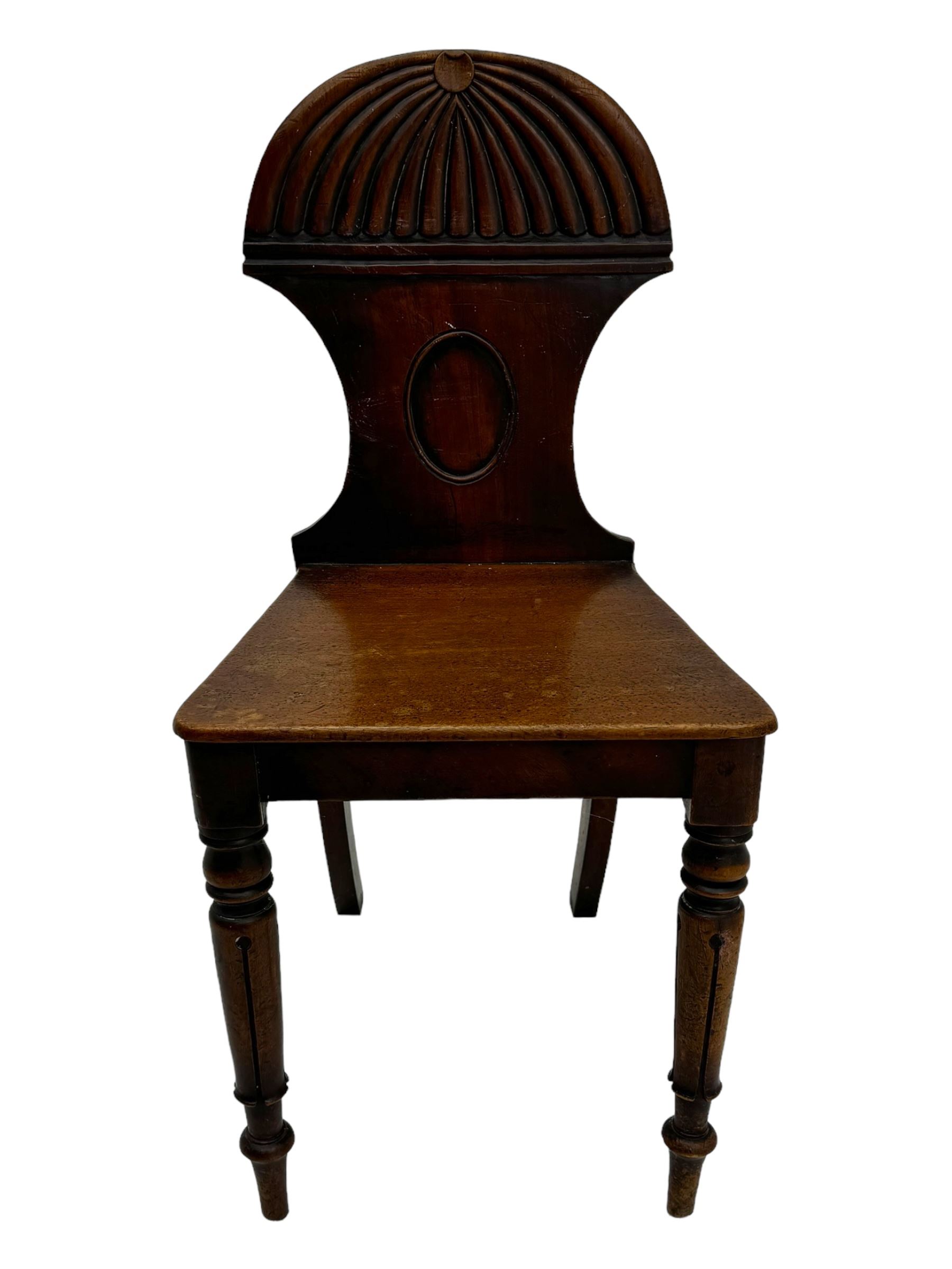 Regency mahogany hall chair, the carved back with shell motif and oval medallion, supported by turned front legs and splayed rear legs