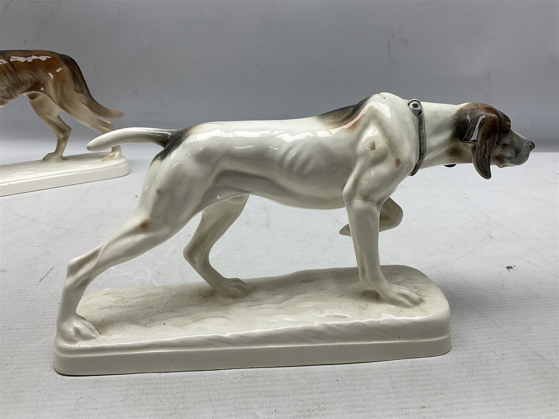 Two Hertwig and Co Katzhutte figures of dogs, comprising a German Shepherd and a pointer dog, both with printed marks beneath, largest H21.5cm W25cm