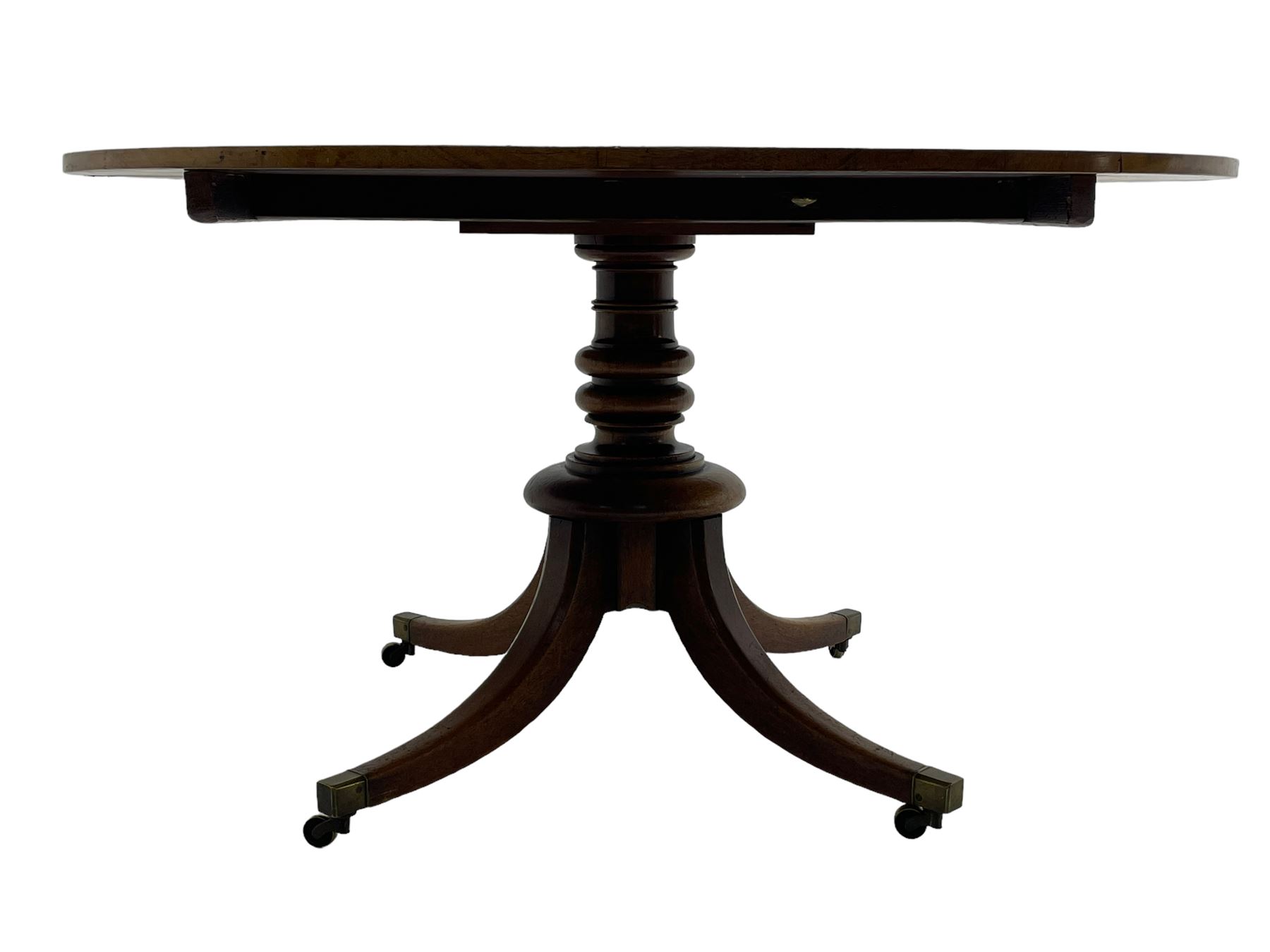 George III mahogany breakfast table, oval tilt-top on turned column with four splayed supports, fitted with brass cups and castors 