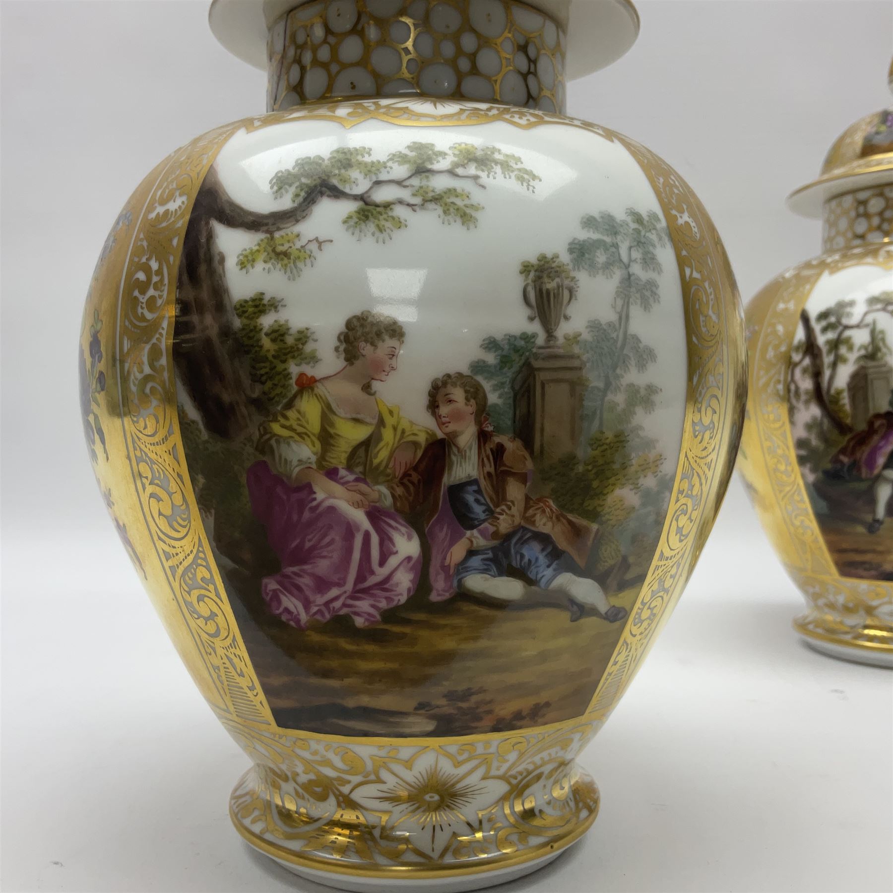 Pair of late 19th century Helena Wolfsohn vases and covers, each of baluster form with domed cover, painted with alternating panels of romantic scenes and floral sprays upon gilt ground, with Augustus Rex mark to base, H27cm