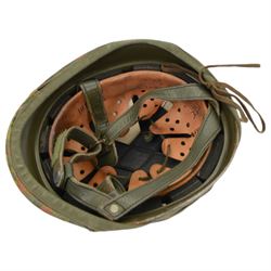 Collection of nine military helmets, including several with camouflage covering 