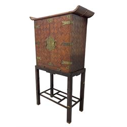 Chinese design bamboo and wood altar cabinet on stand, parquetry lattice-work bamboo, two doors with engraved metal fixtures enclosing drawers and shelf, fitted with slide, the stand pm square supports joined by a series of geometric stretchers