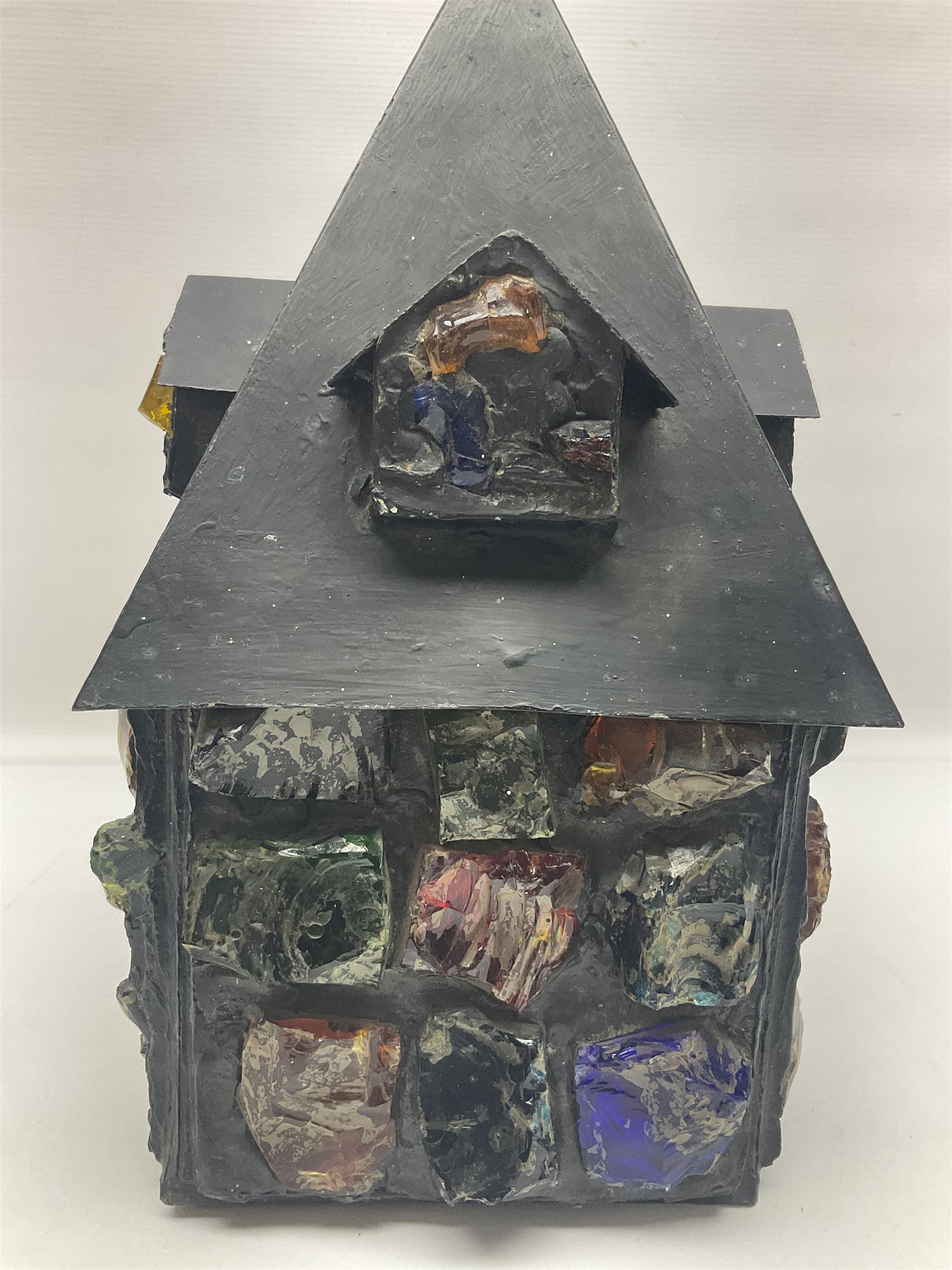 20th Century Arts & Crafts wrought iron porch lantern, in the manner of Peter Marsh, modelled as a house set with coloured resin panels, H38cm