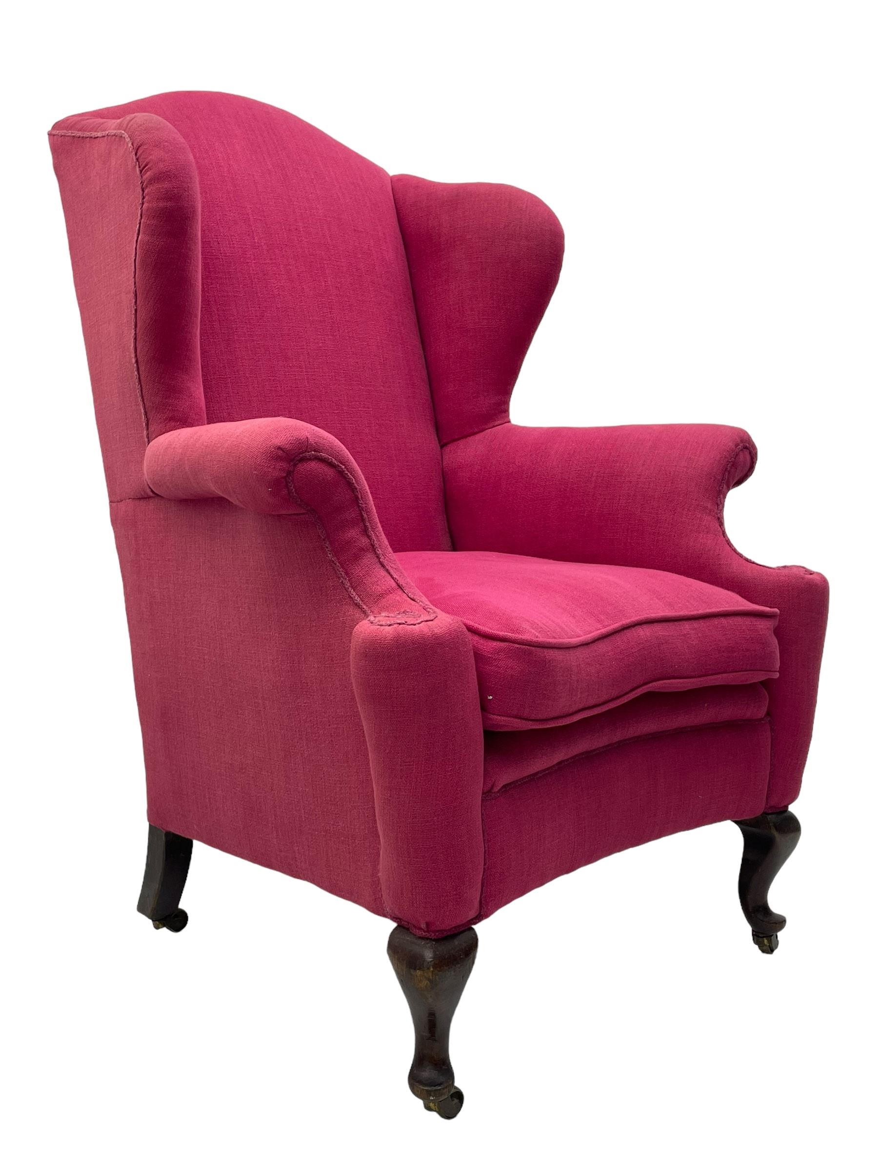 Georgian design hardwood-framed wingback armchair, arched cresting rail over curved wingback, rolled arms on scrolled cushioned supports, reverse bow-front, upholstered in claret red fabric with loose seat cushion, on cabriole front feet and brass castors 