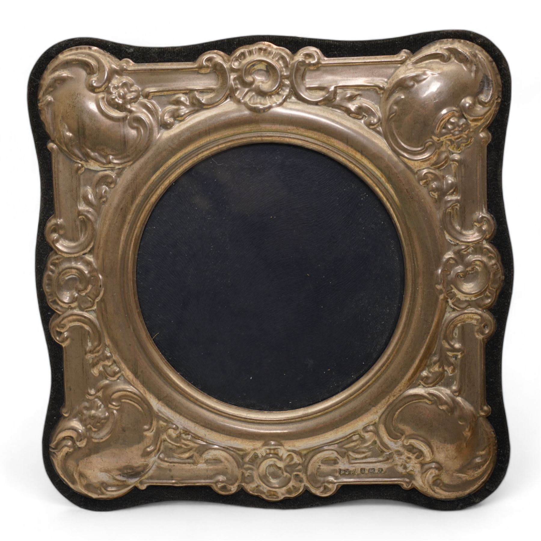 Silver photograph frame with embossed decoration and circular aperture D10cm Birmingham 1984 and a pair of silver backed gentleman's hair brushes Birmingham 1922