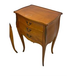 Pair of late 20th century French design cherry wood bedside lamp tables, shaped bombe form, fitted with three drawers, on tapering cabriole supports, decorated with ornate cast gilt metal mounts 