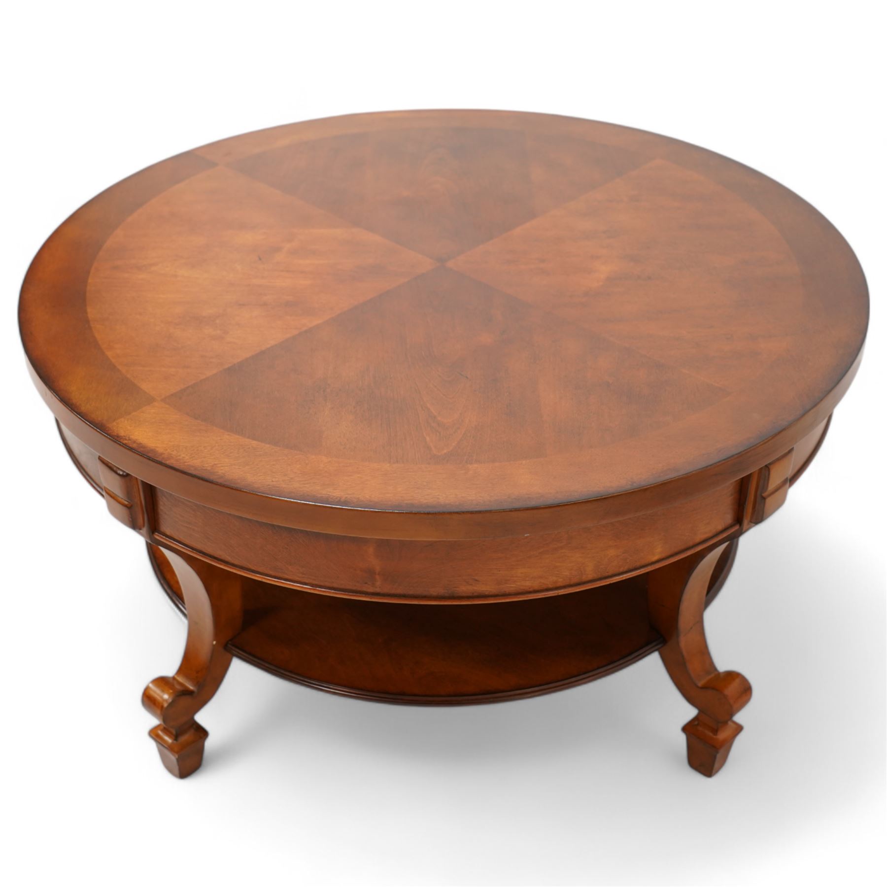 French cherry wood circular coffee table, segment veneered top with crossbanding over plain frieze, curved supports united by magazine under-tier, on spade feet