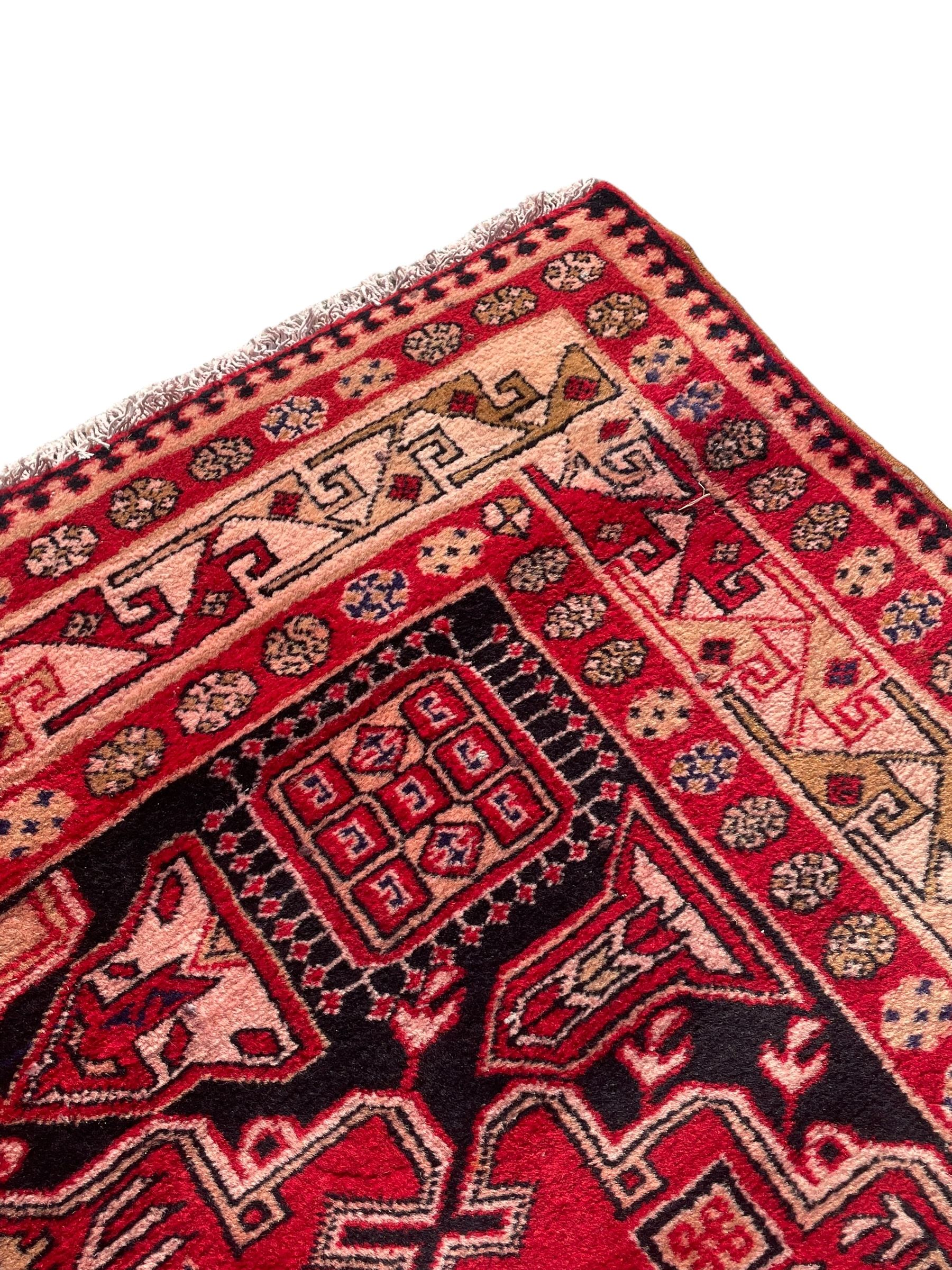 Persian Hamadan indigo and crimson ground rug, the field filled with three shaped medallions, overall geometric design, decorated with sandikli and hac motifs, geometric main border with repeating hooked motifs, within guard stripes decorated with small flower heads, outer crenelated fence band 