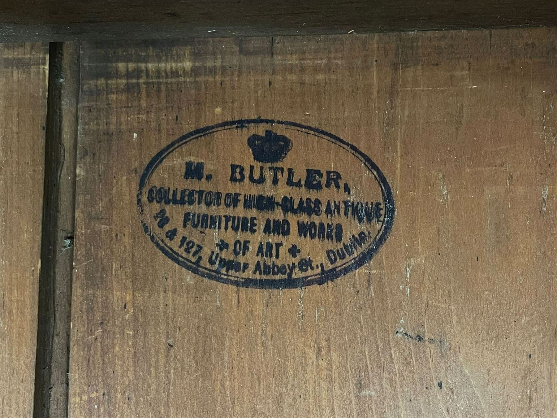 19th century Irish mahogany press wardrobe, projecting dentil cornice over two figured panelled doors, enclosing three sliding trays and hanging rail with coat hooks, fitted with two drawers to base over a shaped apron, raised on acanthus carved cabriole supports with paw feet, retailed by Millar & Beatty of Dublin, with paper labels verso, collected and restored by Michael Butler (1870-1900), impressed stamp to side and ink stamp to drawer inscribed 'M Butler collector of high-class furniture and works of art'