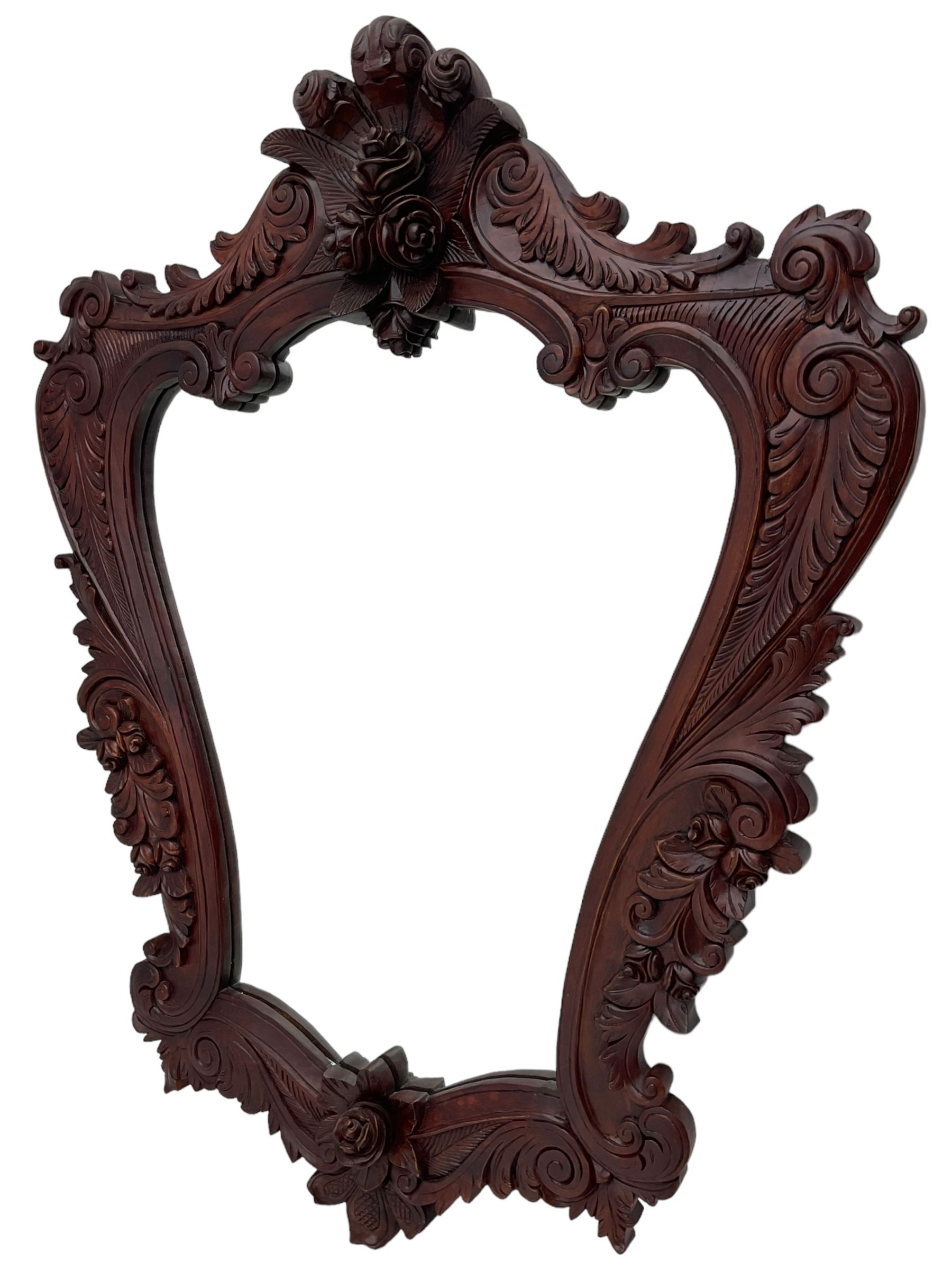 Large carved hardwood wall mirror, shaped floral carved pediment over trailing and scrolled foliage decoration, plain mirror plate 