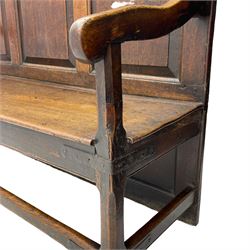 18th century oak settle, the high back with three fielded panels, shaped arms and solid plank seat, standing on square supports joined by stretchers