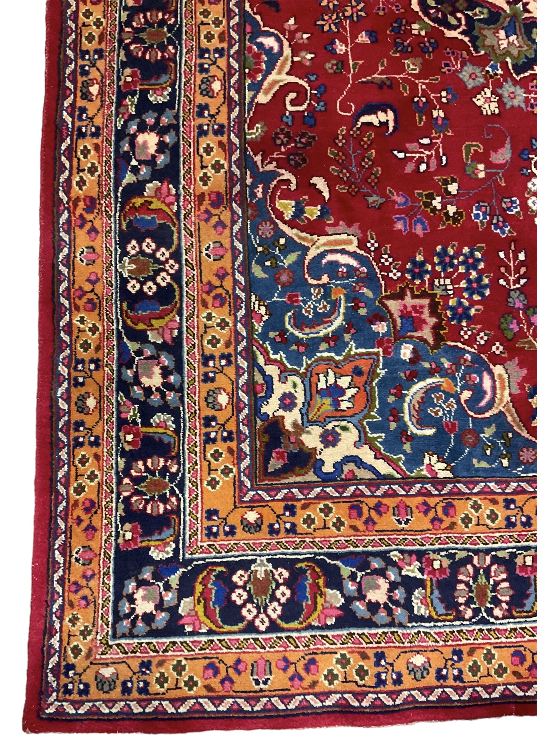 Persian Meshed red ground rug, central floral rosette medallion surrounded by trailing branch and stylised flower heads, repeating scrolling border