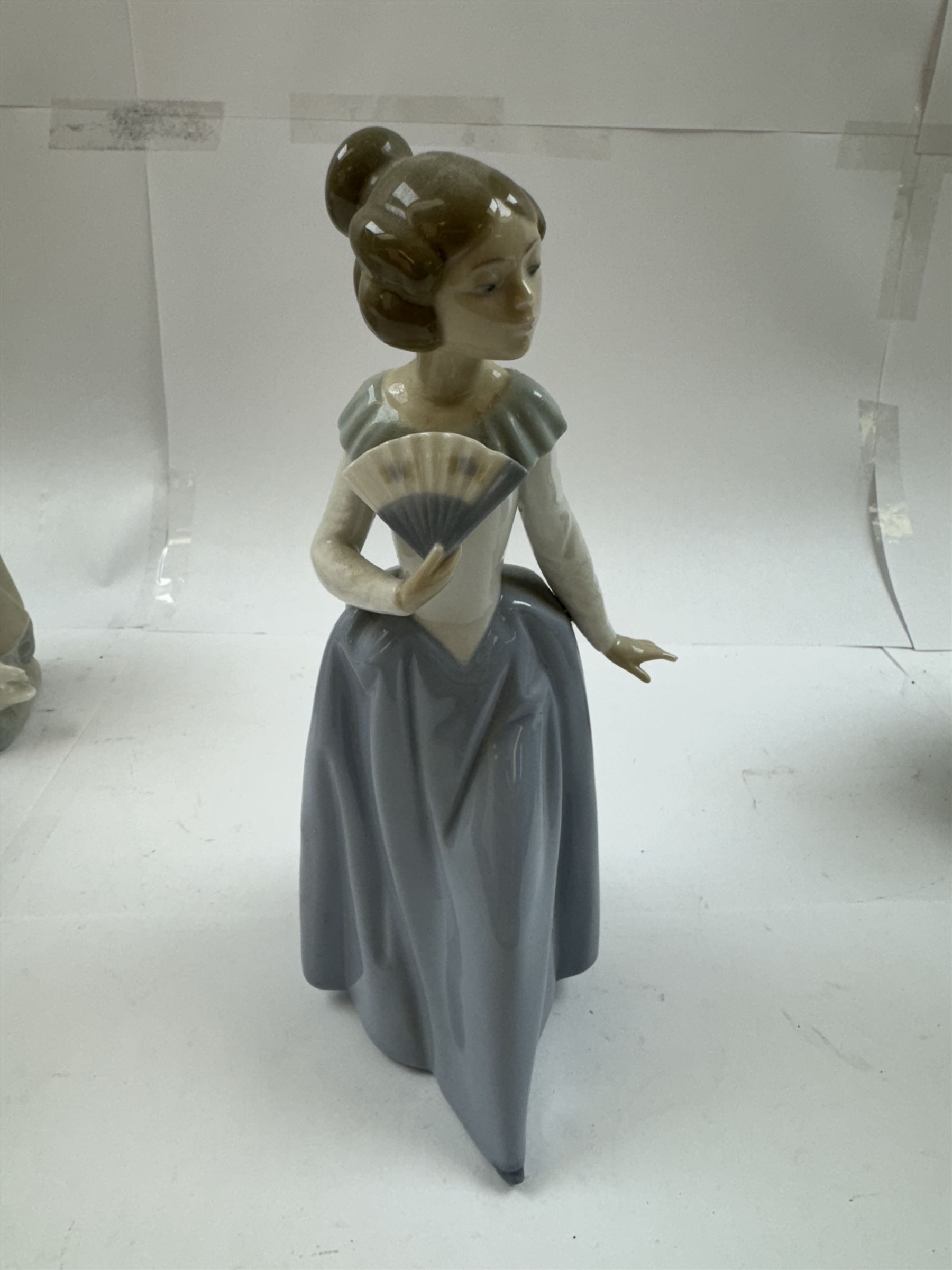 Two Royal Copenhagen figures, comprising girl with cow, 779 and Farmer with scythe, no 685 , together with two Lladro figures, and similar 