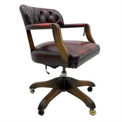 Mid 20th century leather swivel desk chair, oxblood button-tufted upholstery, wooden frame and armrests, on brass castor supports