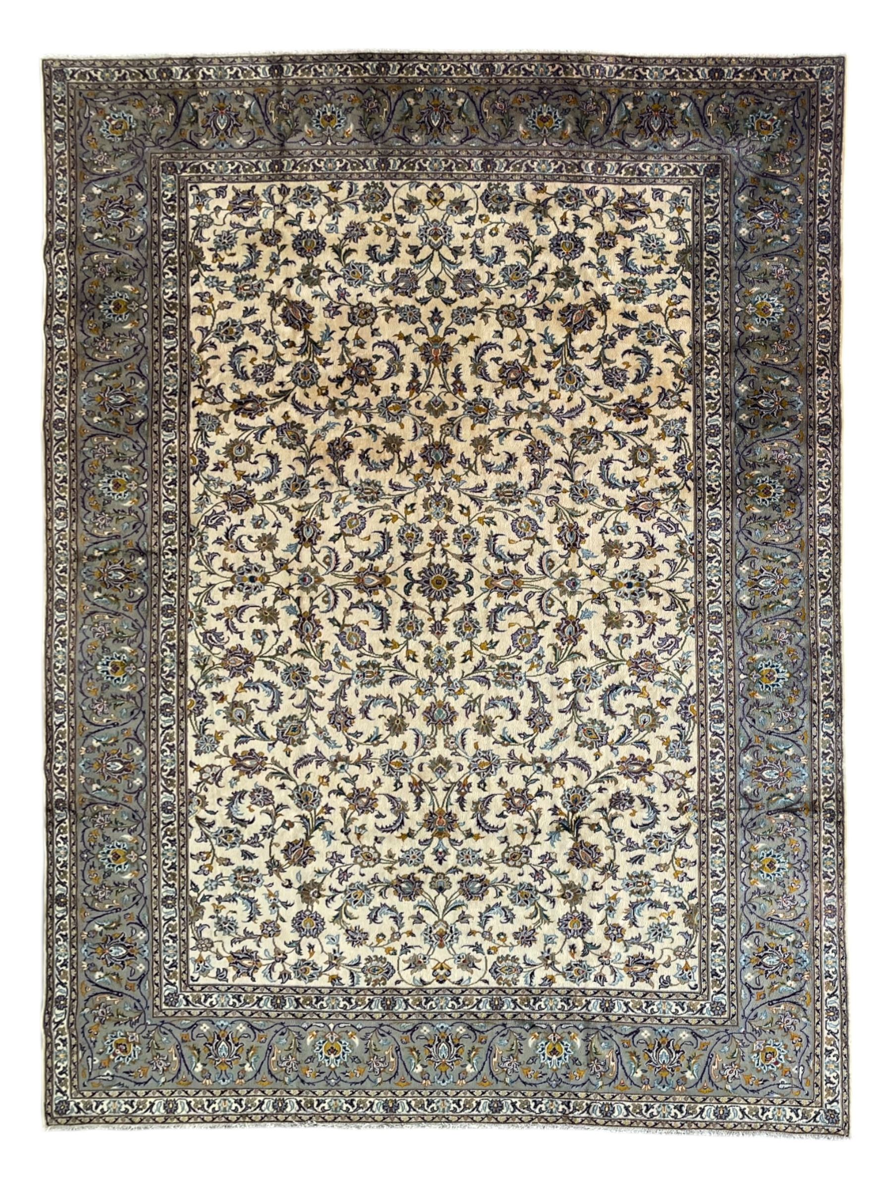 Persian Kashan ivory ground carpet, the busy field decorated with scrolling and interlaced leafy branches and palmettes, trailing branch border with repeating stylised plant motifs, within floral pattern guard stripes 