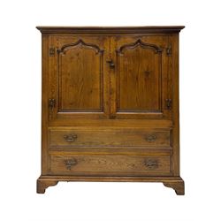 Oak drinks or media cabinet, projecting moulded cornice over two Gothic arch panelled doors on sliding tracks enclosing open storage, two drawers with brass drop handles, on bracket supports