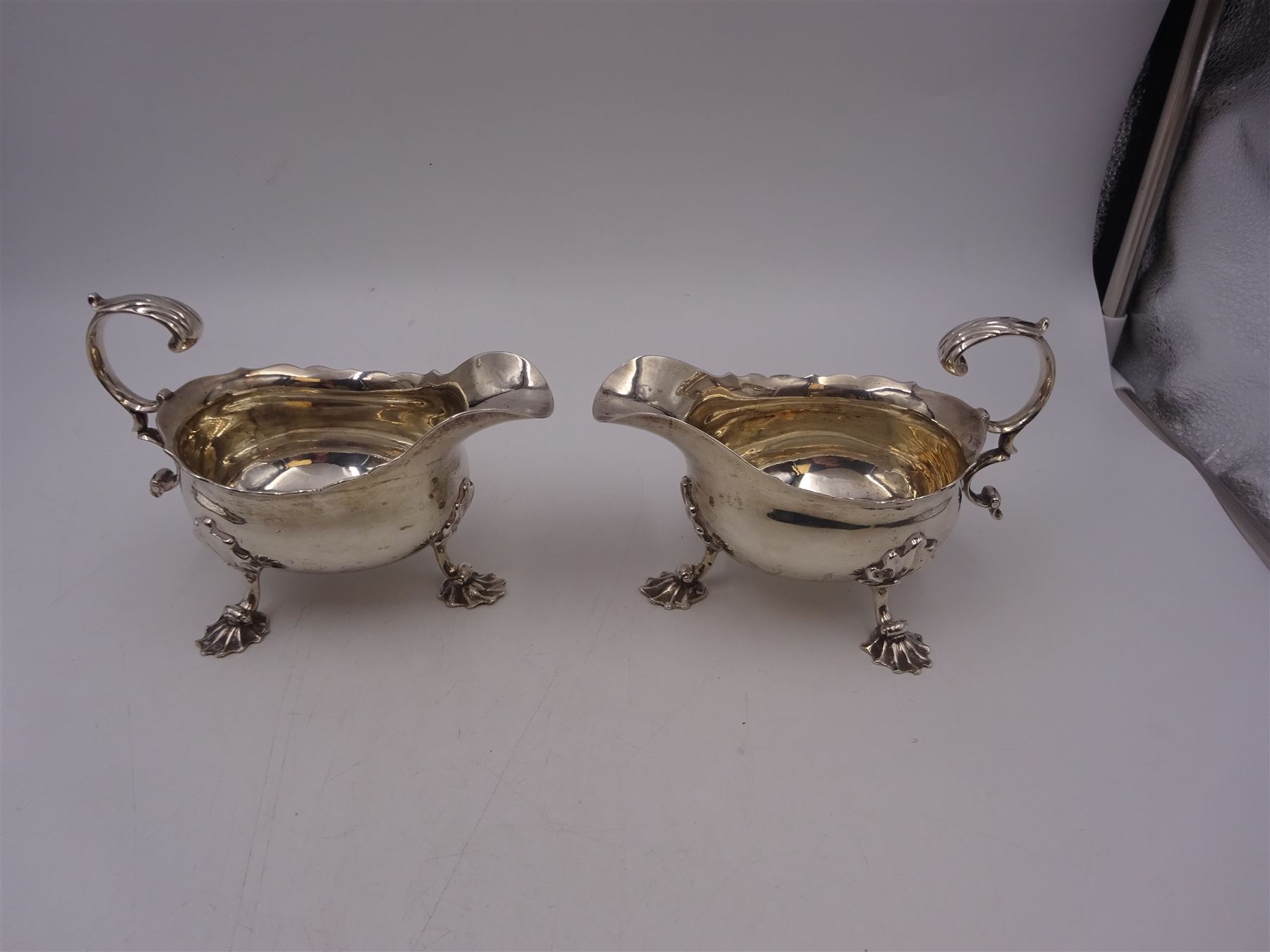 Near pair of George II silver sauce boats, each of oval form with shaped rim and capped flying scroll handle, upon three scroll mounted feet, hallmarked David Hennell, London 1758, H12cm