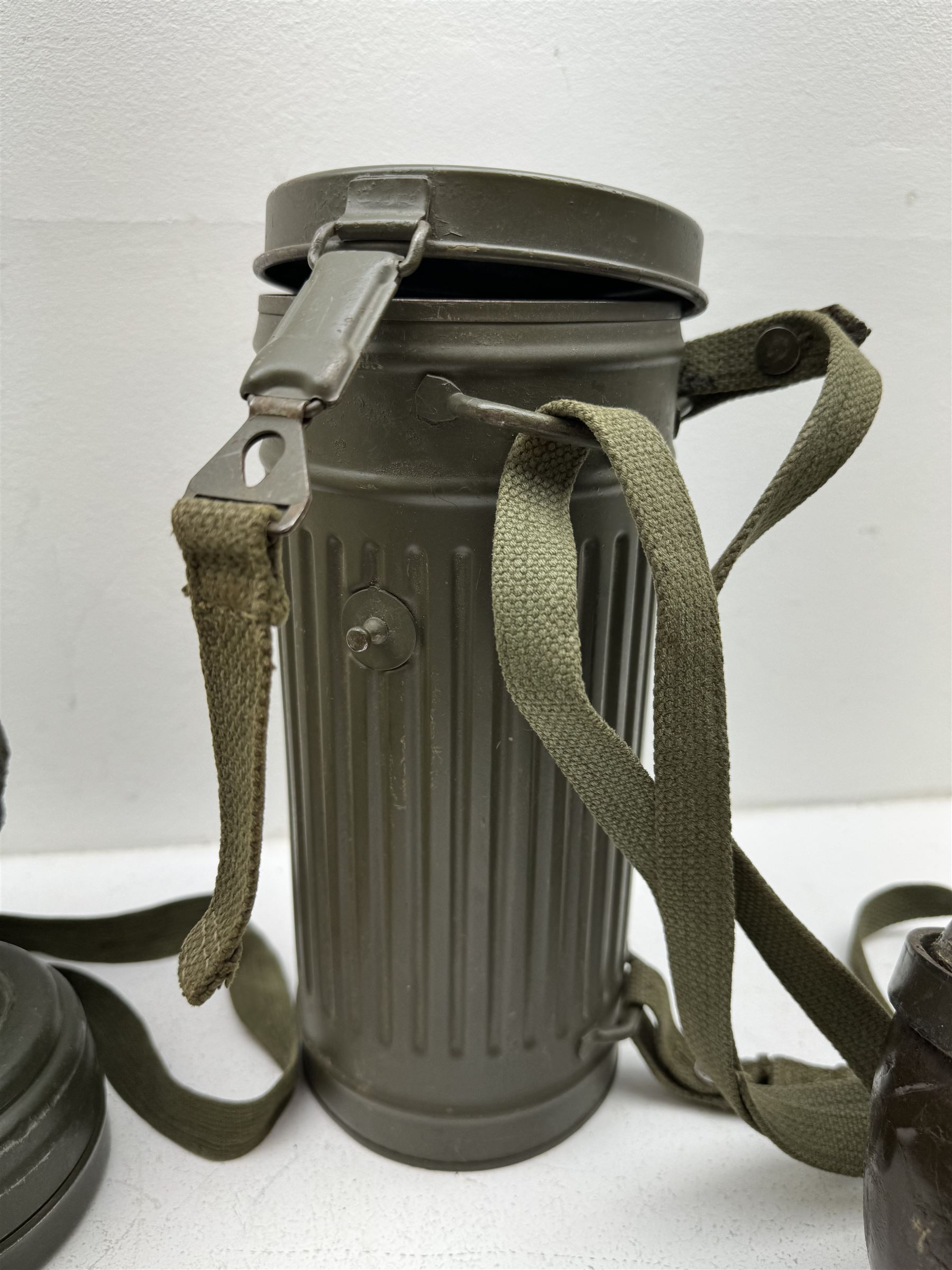 Two WWII German army canteen water bottles, together with German gas mask marked FE55 in a green fluted tin canister