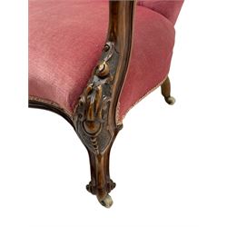 Victorian carved walnut open armchair, foliate carved cresting rail over butted back and sprung seat, upholstered in pink velvet scrolled arm terminals with moulded scrolling vines terminating to cabriole supports and ceramic castors