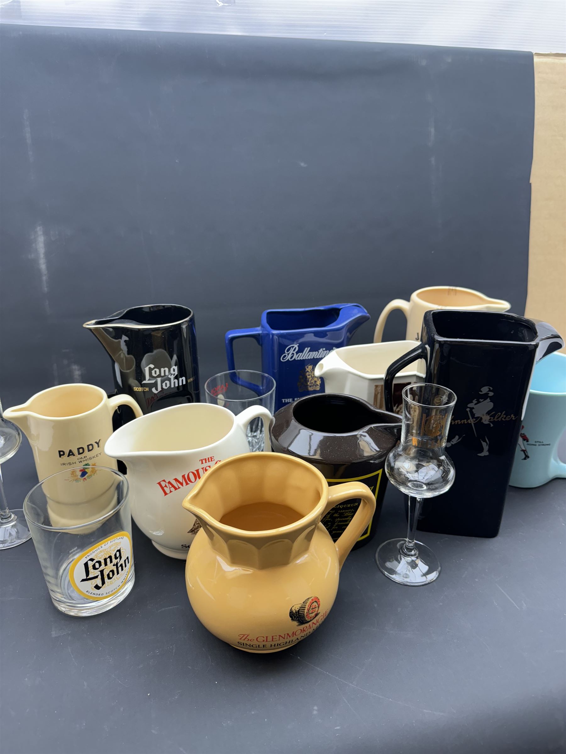 Thirteen ceramic whisky jugs bearing various advertising, including Long John, Jamesons, Ballantines etc, together with whisky glasses 