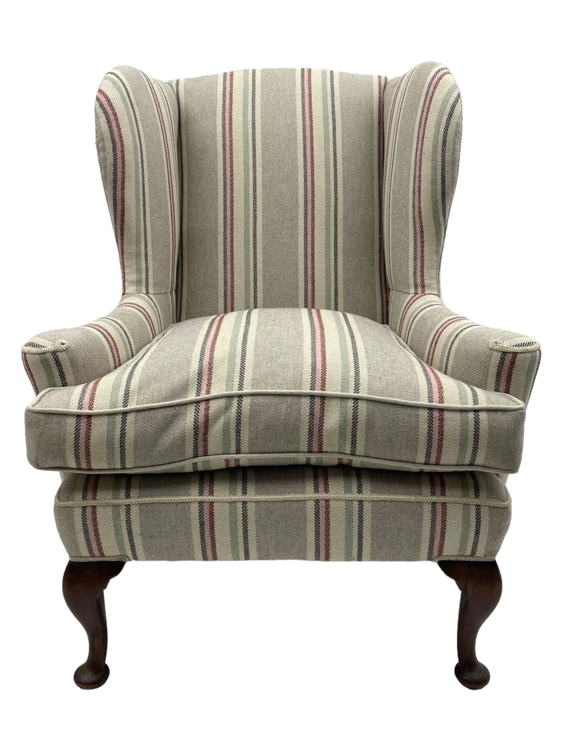 Georgian design hardwood-framed wingback armchair, curved wingback terminating to curved and rolled arms, upholstered in striped fabric with loose seat cushion, on cabriole front feet 