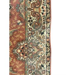 Persian design peach ground carpet, central floral medallion surrounded by scrolling foliage, decorated all over with stylised plant motifs, floral design repeating border