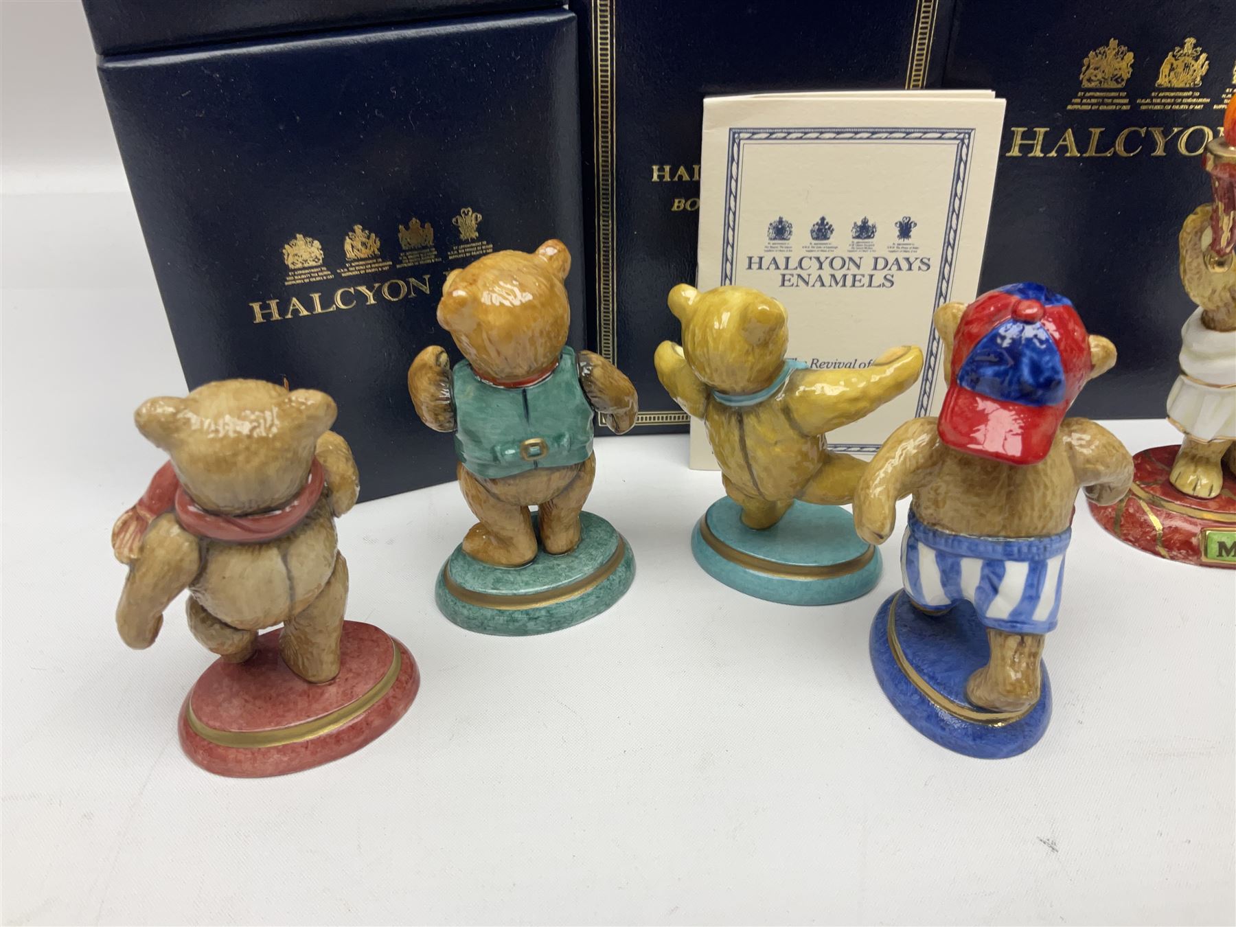 Eight Halcyon Days Teddy Bear of the Year figures, from 1993 to 2000, including one example modelled as a bear in Greek dress carrying a torch, one example modelled as a schoolboy and one example in a blue dress, all boxed 