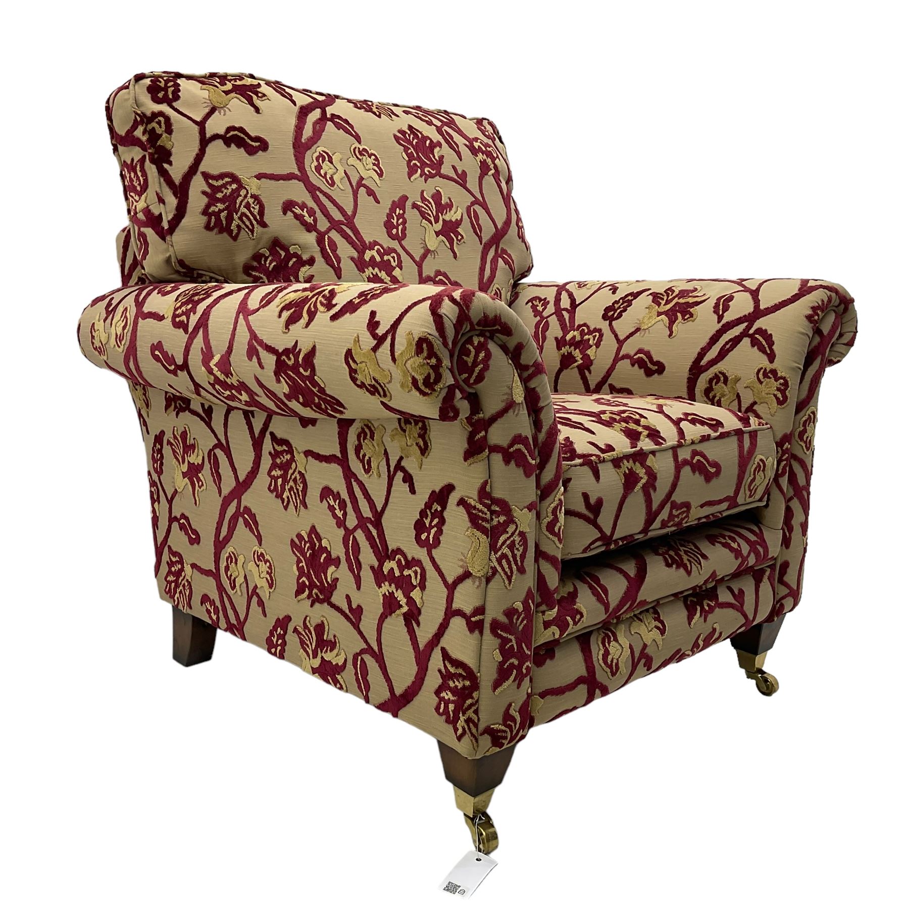 Contemporary upholstered armchair, scroll arms and loose cushions, embossed beige ground fabric with red and gold floral motifs, on tapered wooden supports with front brass castors