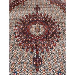 Persian Bidjar ivory and indigo ground rug, large central rosette medallion surrounded by floral herati motifs, crimson ground border decorated with repeating palmettes, within guard stripes decorated with small flower head motifs 