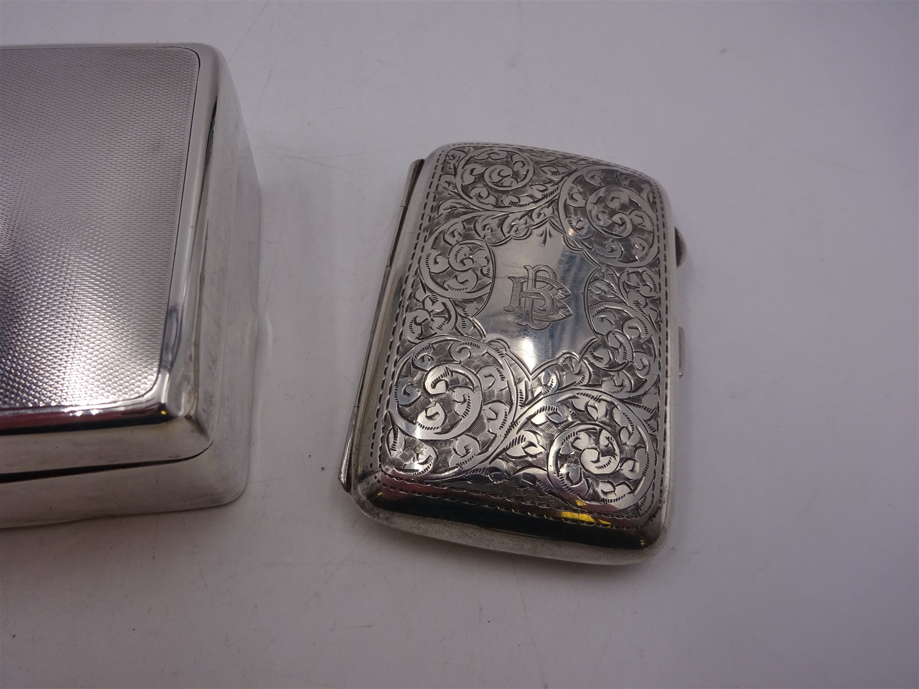 1920s silver cigarette case, of rectangular form with rounded corners, engraved with initials to front cover and scrolling decoration throughout, hallmarked John Rose Birmingham 1922, together with a 1930s silver mounted cigarette box, of plain rectangular form, with engraved initials and engine turned decoration to hinged cover, opening to reveal a softwood lined interior, hallmarked William Neale & Son Ltd, Birmingham 1939, box H3.5cm