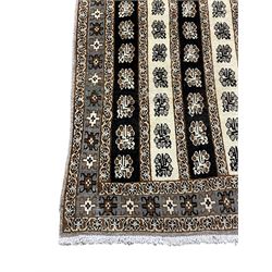 Persian ivory ground rug, the field divided into stripes decorated with stylised flower heads, the border with repeating cross motifs within guard stripes 