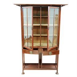 Edwardian mahogany glazed display cabinet, projecting cornice over astragal glazed doors enclosing three velvet lined shelves, over two bow-front drawers with Tunbridge Ware style inlaid stringing, on pierced end supports united by undertier