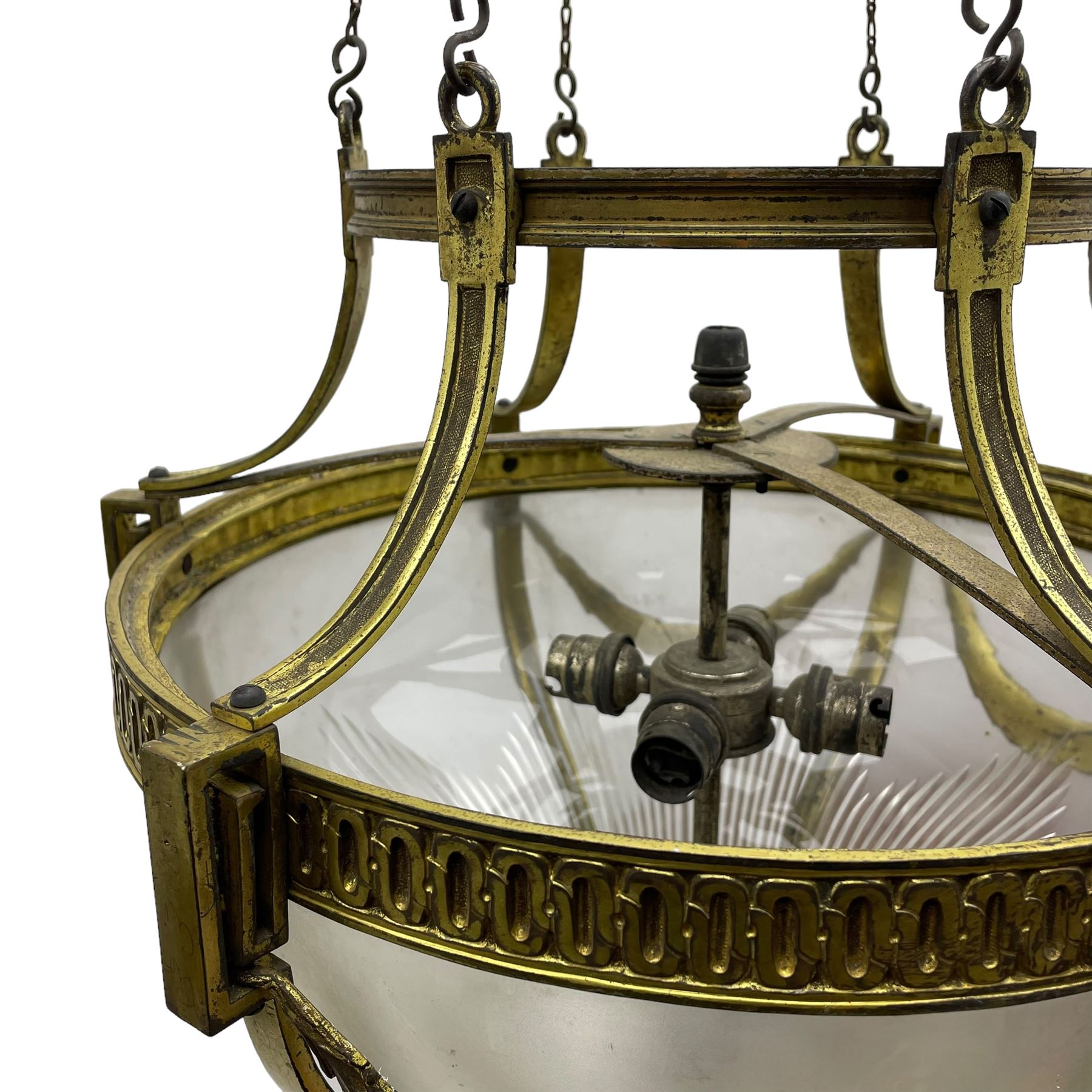 Edwardian brass ceiling light of circular bulbous form, moulded upper band over a guilloche cast central band united by shaped strapping, decorated with fruiting foliage festoons, fitted with frosted and vertical bevelled glass bowl, acanthus cast finial 