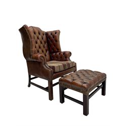 Georgian design hardwood-framed wingback armchair, shaped cresting rail and deep wingback over rolled arms, upholstered in brown buttoned leather with studwork bands, the seat cushion upholstered in checkered fabric, on square supports united by stretchers (W86cm, H118cm, D86cm); together with matching rectangular footstool (63cm x 43cm, H37cm) 