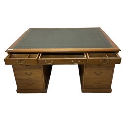 Late 19th century twin pedestal oak partner's desk, rectangular top with inset green leather writing surface, fitted with nine graduating drawers to each side, the rear drawers enclosed by panelled cupboards