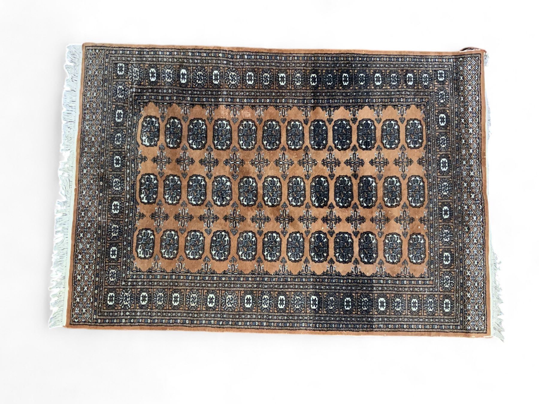 Afghan Bokhara rust ground rug, decorated with three columns of Gul motifs, the wide guard band with further scrolling and geometric designs (183cm x 129cm); together with a Persian design indigo ground rug (W170cm x 117cm)